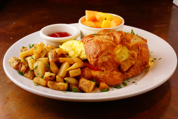 Croissant sandwich with eggs, potato persillade and seasonal fruit at La Creperie Cafe