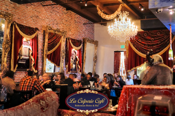Dining room at La Creperie Cafe with chandelier, red drapes and gilded mirrors