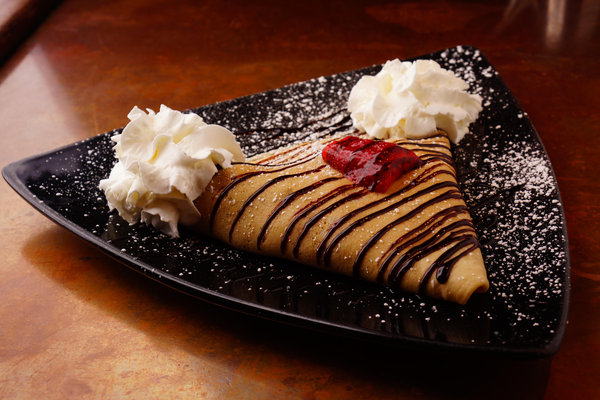 Sweet crepe with chocolate drizzle, strawberry and whipped cream at La Creperie Cafe